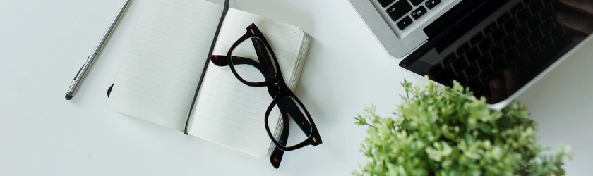 photo of glasses lying next to a computer and plant